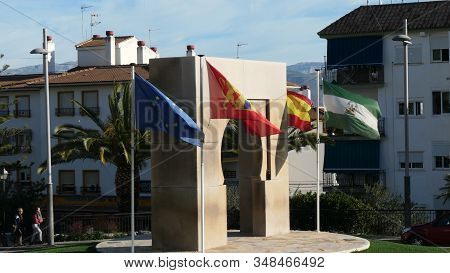 Alora, Spain - January 30, 2020: Flags Of Eu, Spain, Andalusia And Alora On Windy Day By Arabic Arch
