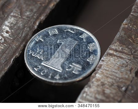 Top View Of The One Yuan Coin In A Metal Vise. Currency And Economics Under The Onslaught, The Conce