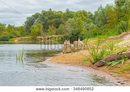 Sandbank In The River In The Form Of Beach With Built Sandy Locks On A Background Of Steep Cliffs, O