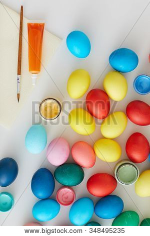 Above View Of Multi Colored Easter Eggs With Paint Brushes Arraigned In Minimal Composition On White