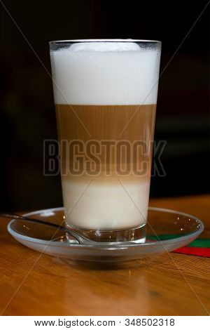 Hot Latte Coffee In Tall Translucent Glass On Wooden Table On Black Background, Vertical Photography