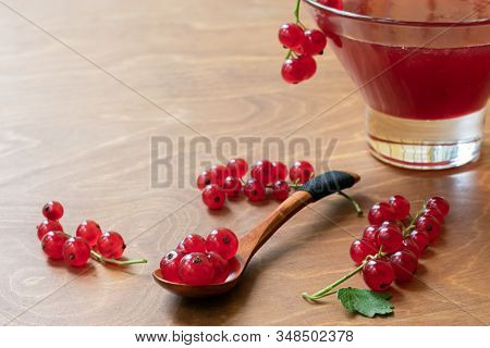 Glass Bowl Of Red Current Jam With Wooden Spoon Full Of Many Ripe Juicy Red Current Berries On Dark 