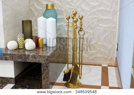 Separate parts of the interior of the living room. Fireplace and poker with reflection in the mirror. By the fireplace there are a variety of candles.