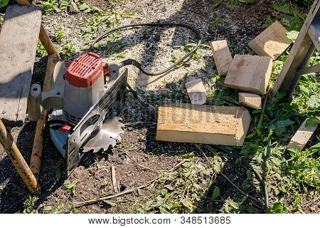An Electric Manual Circular Saw Is Lying On The Ground Near Scraps Of Wood Planks With Non Complianc