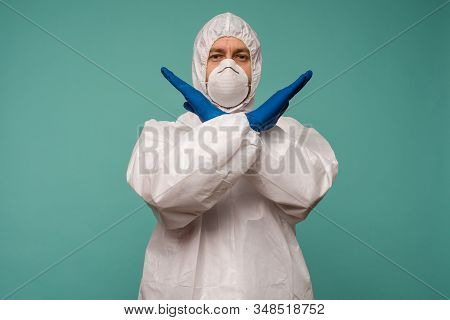 A Male Doctor In Protective Overalls And A Mask Shows Stop Sign. Coronovirus Protection Concept In C