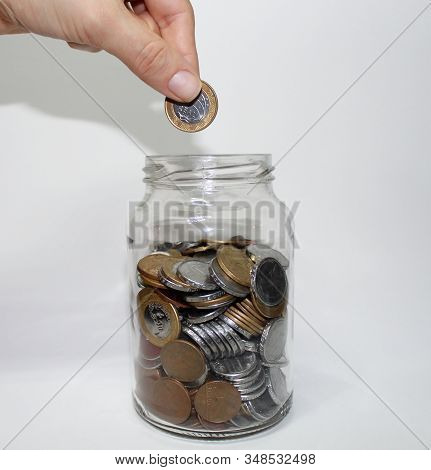 Hand Putting Coins Into The Pot, Saving Money For The Future.