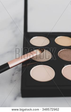 Close-up Of Brush On Top Of Eyeshadow Palette With Trendy Nudes And Bronzy Tones
