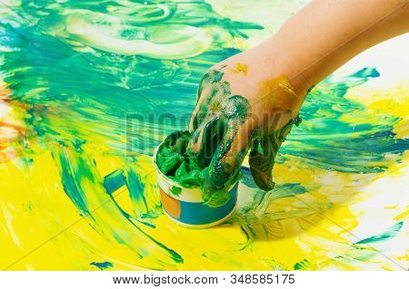 Smeared Childrens Fingers Are Diped In Tube With Green Paints On The Background Of Colored Paper