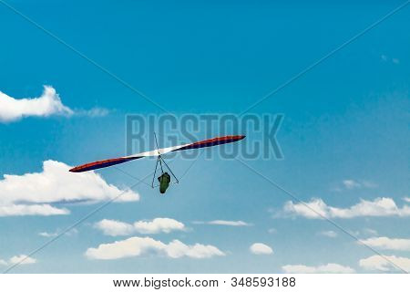 The Extremal Hobby Of A Brave Person. Soaring Hang Gliding Flight Through The Puffy Clouds In The Sk