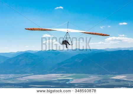 Hang Glider Man Flying In Clear Sunny Day. Flight Over Kootenay Valley Mountains, Creston, British C