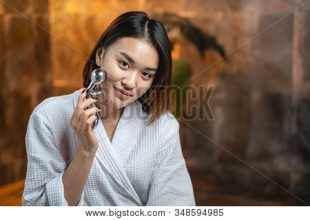Asian Pretty Woman Using Modern Massagers For Facebuilding