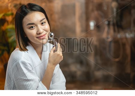 Asian Cute Woman Using Modern Massagers For Facebuilding