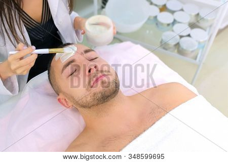Cosmetologist Is Applying White Moisturizing Mask On Mans Face Using Brush In Beauty Clinic, Face Cl