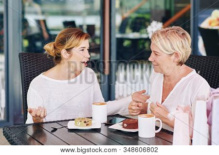 Pretty Young Woman Telling Shocking News And Gossips To Her Mother When Thay Are Having Coffee And D
