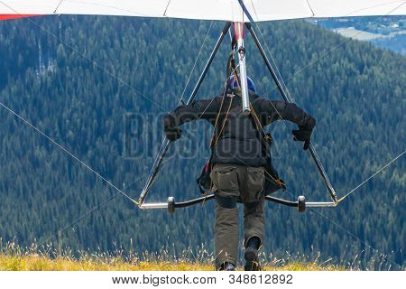 Back View Of Professional Hang Glider Man Running And Taking Off. Hang Gliding In Action - Flying Fr
