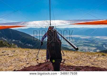 Man With Hang-glider Running For Taking Off The Ground At The Top Of Mountain Hill. Paraglider Ready