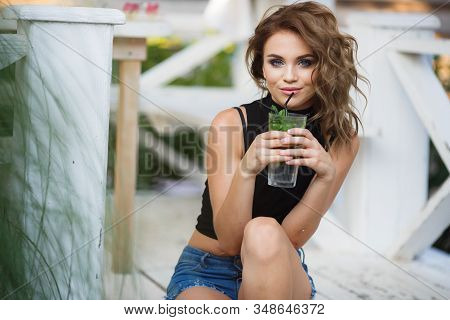 Beautiful Young Woman Enjoy Enjoys A Smoothie And Relax On Tropical Beach With Palm Tree. Summer Vac