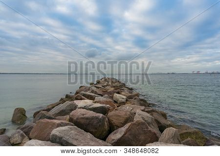 Rock Pier And Calm Water Nature Background With Cloudy Sky. Calm Minimalistic Nature Scene