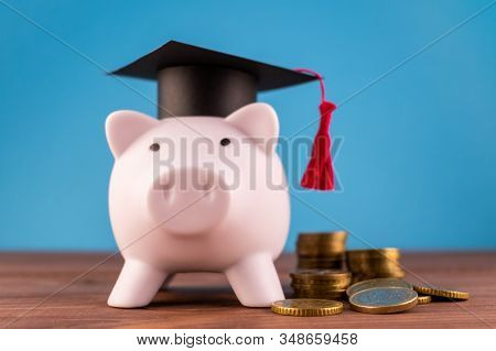 Piggy Bank With A Graduation Hat And A Lot Of Coins On A Light Blue Backround. Student Scolarship Sa