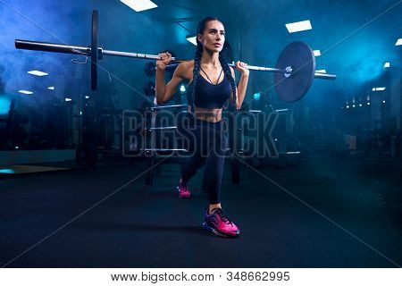 Front View Of Brunette Female Bodybuilder With Braids Doing Squats, Holding Barbell On Shoulders. Sr