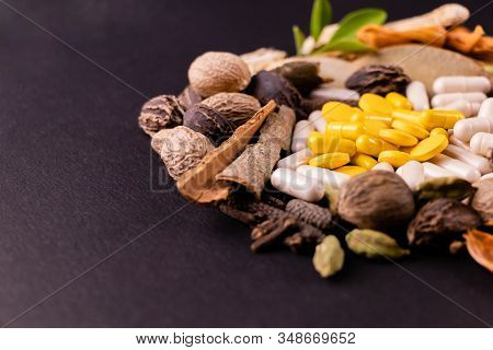 Close-up Of Yellow Herbal Capsules, Tablets And Natural Herbs On Black Background With Copy Space. H