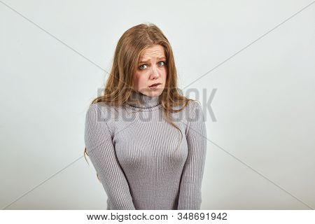 A Young, Beautiful, Red-haired Woman In A Gray Sweater Looks Guiltily Ahead, Her Eyes Narrowed And H