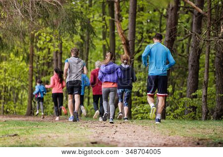 Rear View Of Large Group Of Multi Generation People Running In Nature.