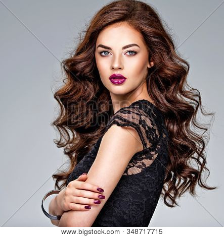 Beautiful woman with long curly hair and vivid purple make-up. Long hairstyle. Young caucasian gorgeous adult girl. Model. Closeup woman's portrait. Bright make-up. Sexy female. Violet lips.