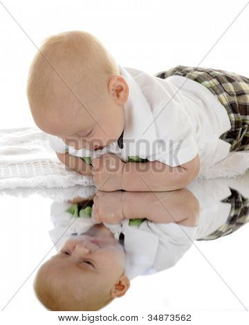 Un enfant lui-même en regardant dans un miroir au-dessous de lui.  Sur un fond blanc.
