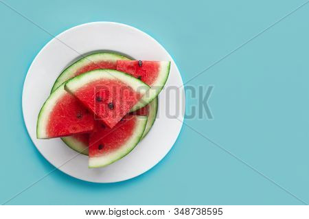 Fresh Sweet Slices Of Ripe Red Watermelon On White Plate On Blue Background. Top View, Flat Lay. Cop