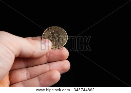 Bitcoin Coin In A Hand On A Black Background. Stock Photo Man Holding A Coin.