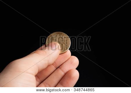 Bitcoin Coin In A Hand On A Black Background. Stock Photo Man Holding A Coin.