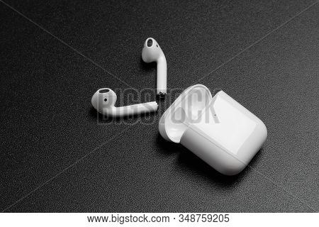 Air Pods With Wireless Charging Case. New Airpods 2019 On Black Background. Entangled 3.5 Headphones