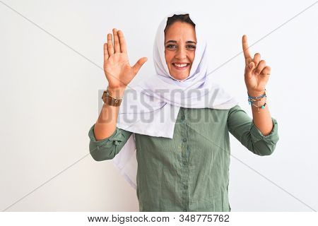 Young beautiful Arab woman wearing traditional Muslim hijab over isolated background showing and pointing up with fingers number six while smiling confident and happy.