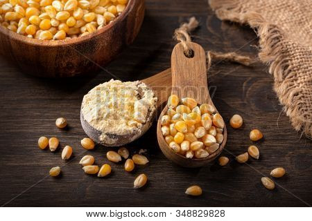 Corn flour in a wooden spoon isilated on a wooden background