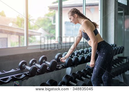 Young Woman Weightlifter Lifting Bench Press Working Out With Dumbbell In The Gym.