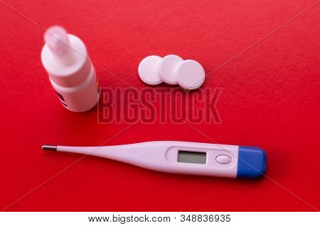 Electronic Thermometer, Spray And Pills On A Red Background. Means For Treating Flu And Colds, Lower
