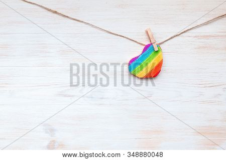 Rainbow Heart Shape Pillow On Clothespin Hanging On Branch With Fresh Leaves, Rustic Wood Background