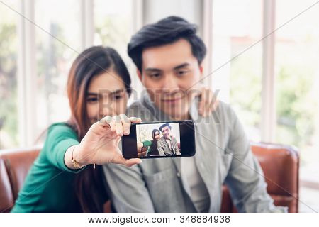 Portrait Of Young Couple Love Capturing Selfie On Mobile Phone At Their Home, Attractive Asian Coupl