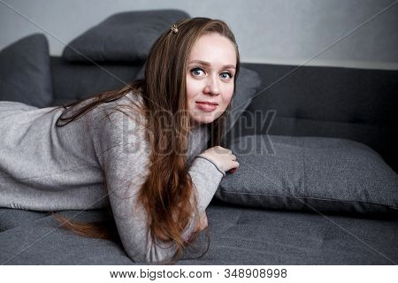 Close-up Portrait Of Young Self Assured Female In Gray Home Interior, Hugge Style, Modern Trendy Att
