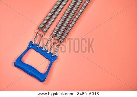 Espander Spring With Blue Handle On Pink Background