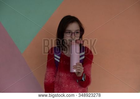 Girl With Cup. Schoolgirl Girl In Glasses Drinks Water From A Thermomug.a Schoolgirl Drinks Tea, Jui