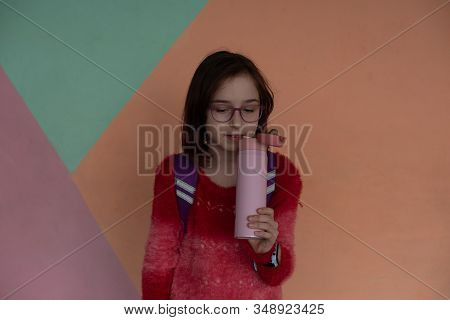 Girl With Cup. Schoolgirl Girl In Glasses Drinks Water From A Thermomug.a Schoolgirl Drinks Tea, Jui