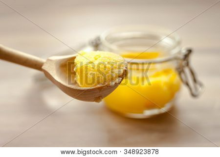 Ghee Clarified Butter Desi Yellow Color In Glass Jar With Spoon Made From Wood On Natural Wooden Bac