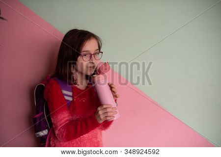 Girl With Cup. Schoolgirl Girl In Glasses Drinks Water From A Thermomug.a Schoolgirl Drinks Tea, Jui