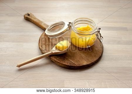 Ghee Clarified Butter Desi Yellow Color In Glass Jar With Spoon Made From Wood On Natural Wooden Bac