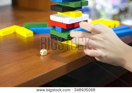 The Hand Dismantles The Tower Of Multicolored Wooden Bars. Concept: Children's Leisure, Board Games,