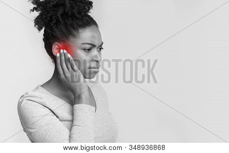Tinnitus. Side View Of Sick Black Woman Having Ear Pain, Touching Her Painful Head, Monochrome Photo
