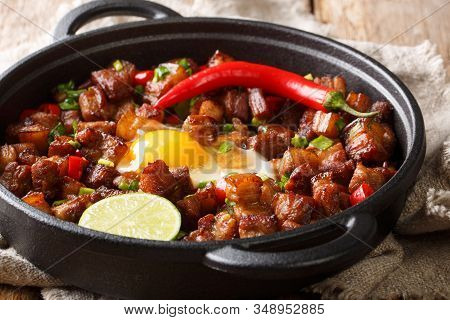 Spicy And Sizzling Pork Sisig Is A Favorite For Filipinos Close-up In A Pan. Horizontal