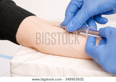Close-up shot of doctor or nurse taking a blood sample from arm vein with a vacutainer. Venipuncture or venepuncture procedure